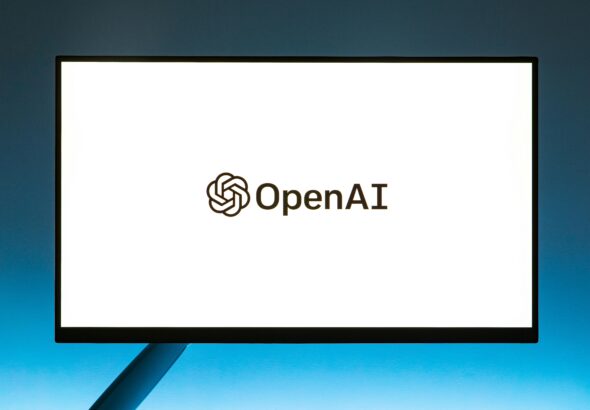 Minimalistic display of OpenAI logo on a monitor with a gradient blue background, representing modern technology.