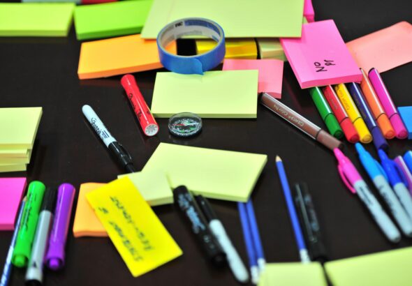 Colorful assortment of office supplies on a desk, including sticky notes, pens, and markers.